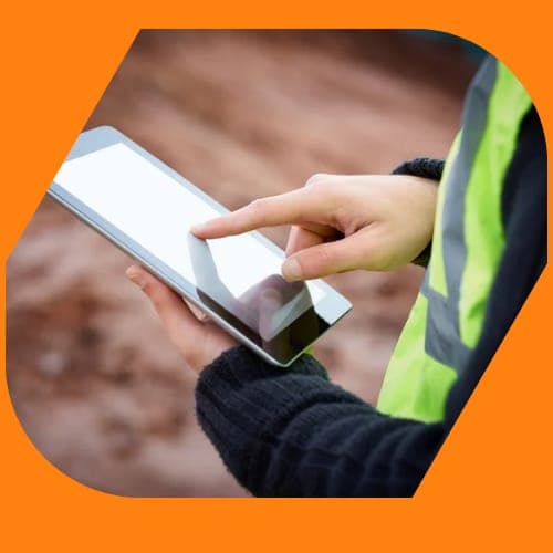 A DantX site manager reviewing a job on a tablet in hi-vis