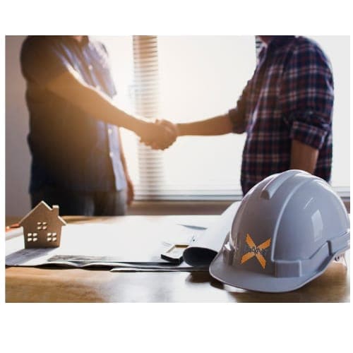 A DantX handshake over project drawings beside a branded hard hat