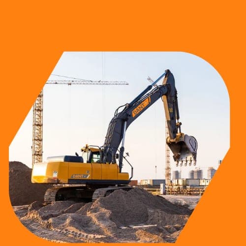 A DantX-branded excavator working a large site beside a tower crane